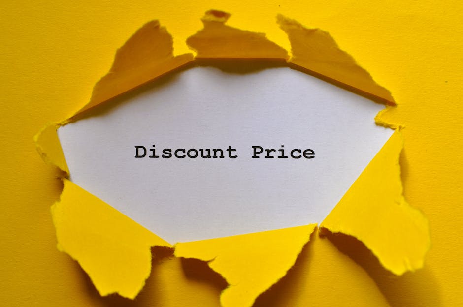 A sheet of white paper with the words 'Discount Price' typed in black, positioned inside a torn hole in a yellow background. The torn edges of the paper reveal the bright yellow surface beneath, with